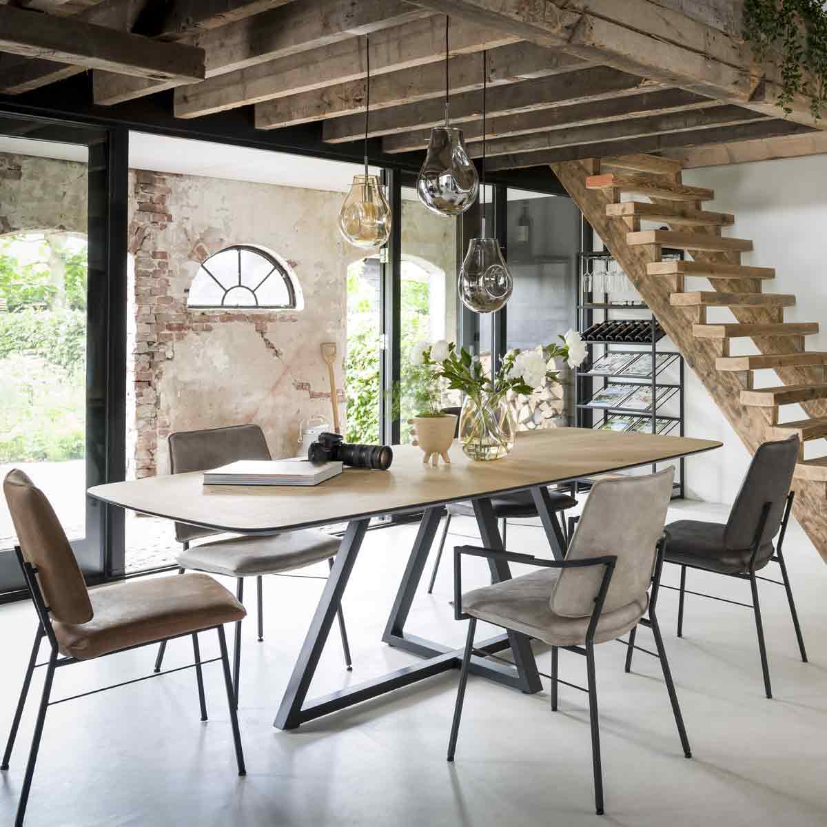 Industriele eethoek met een houten tafel en vijf verschillende stoelen in natuurtinten