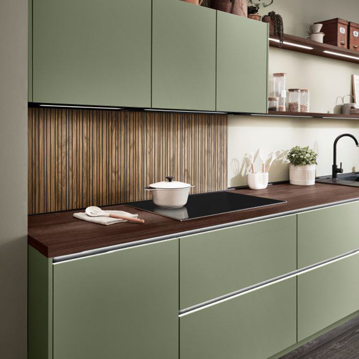 Groene keuken met donker houten werkblad, verticale houten achterwand en zwarte kraan