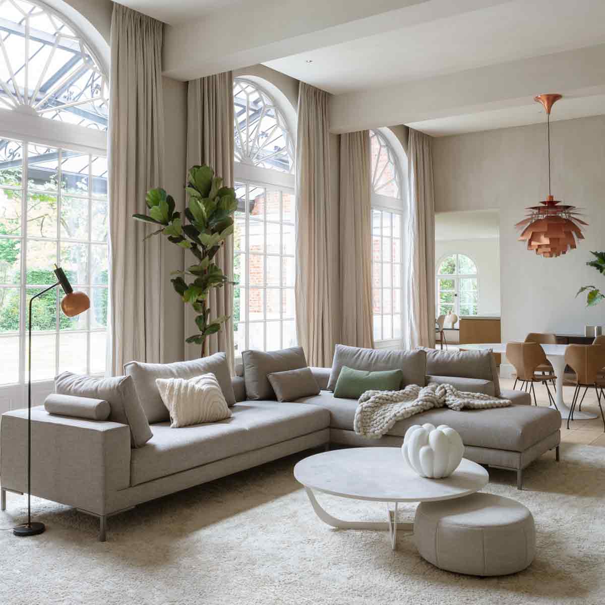 zijkant van een hoekbank in een grijze kleur met salontafels en woonaccessoires