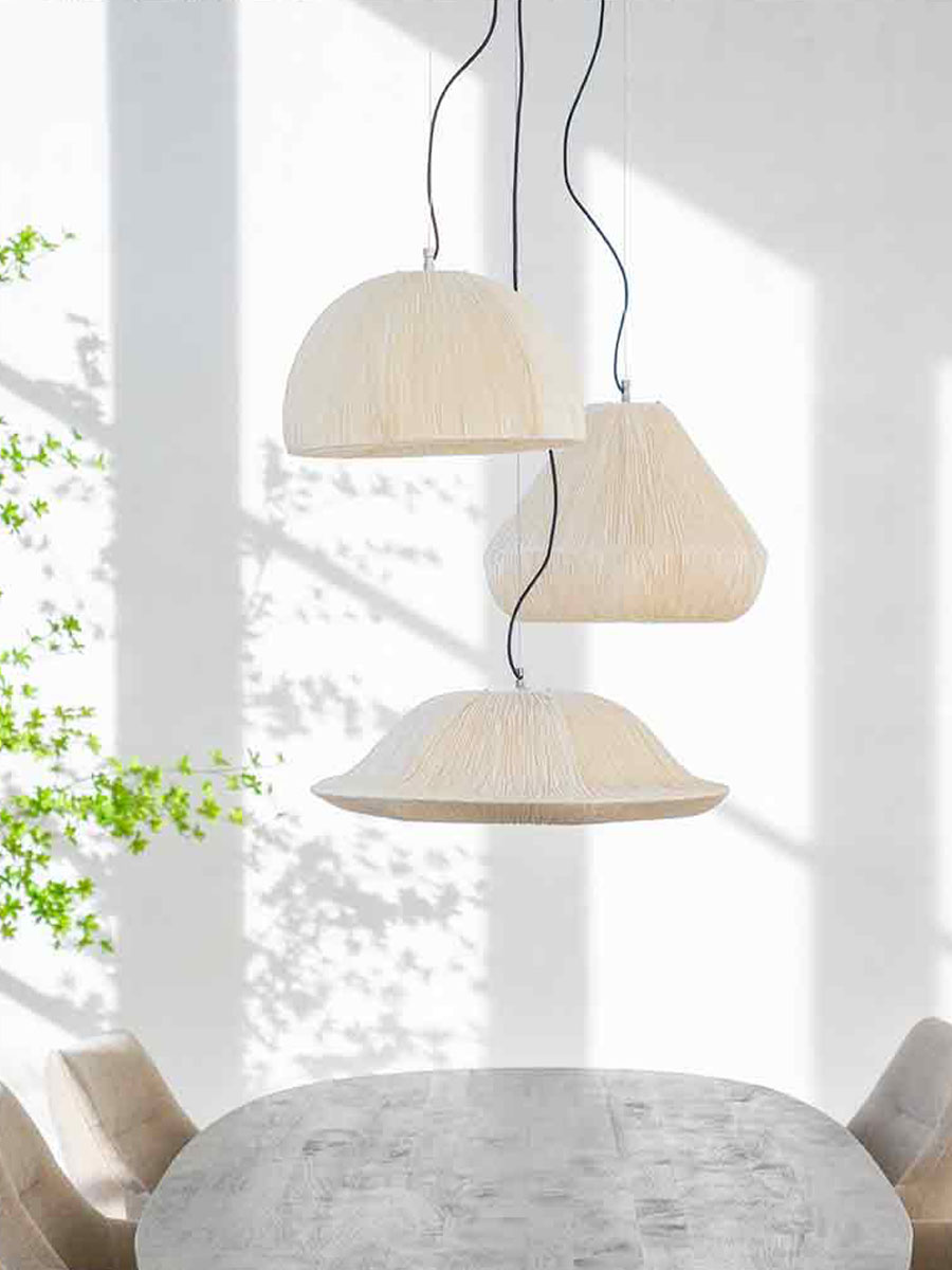 Drie moderne hanglampen in lichte stof met organische vormen, boven een ovale houten tafel in een ruimte met witte wanden en zacht invallend daglicht.