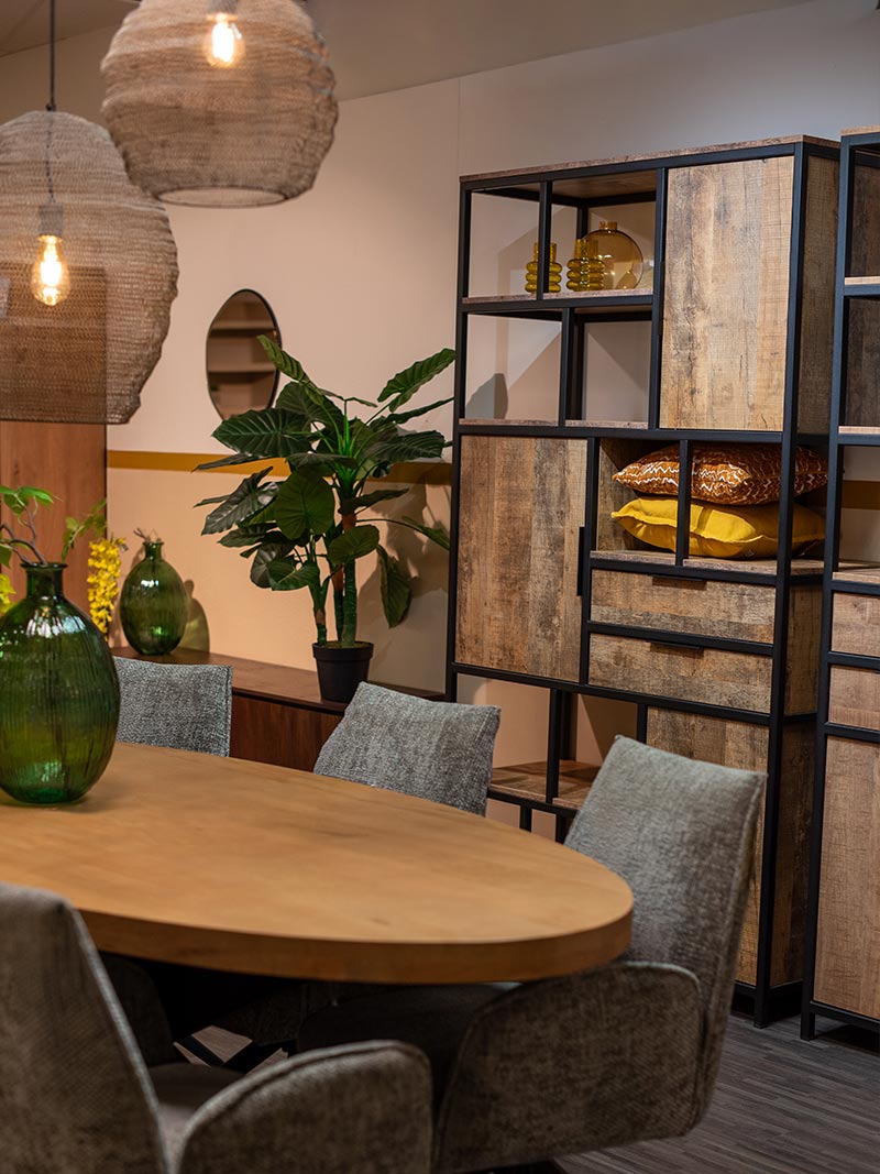 Houten eettafel met grijze stoelen, industri&euml;le kasten, groene vazen, kamerplant en hanglampen als industrieel interieur