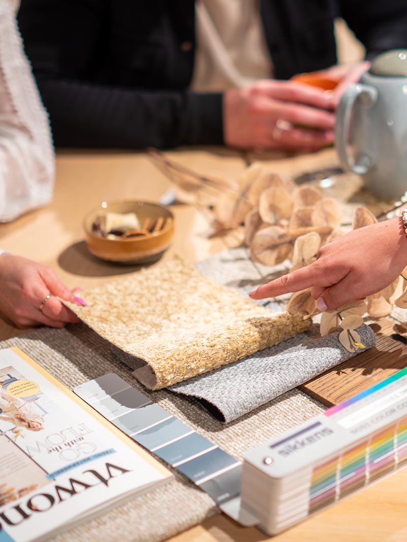 gratis interieuradvies gesprek met stoffen, kleurstalen, woonmagazine en decoratie op houten tafel