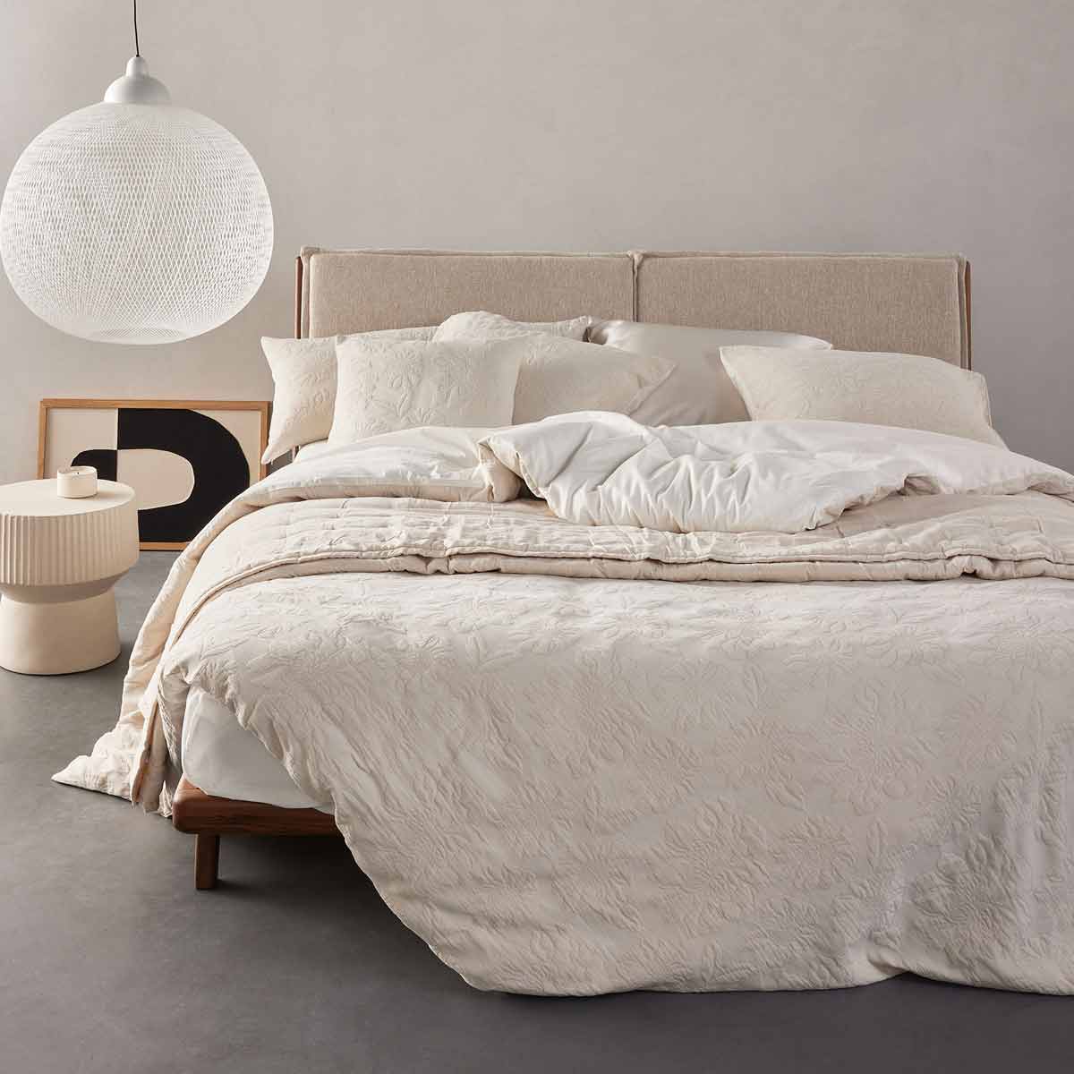 Opgemaakt bed in de woonstijl Japandi stijl met beige tinten en een hanglamp