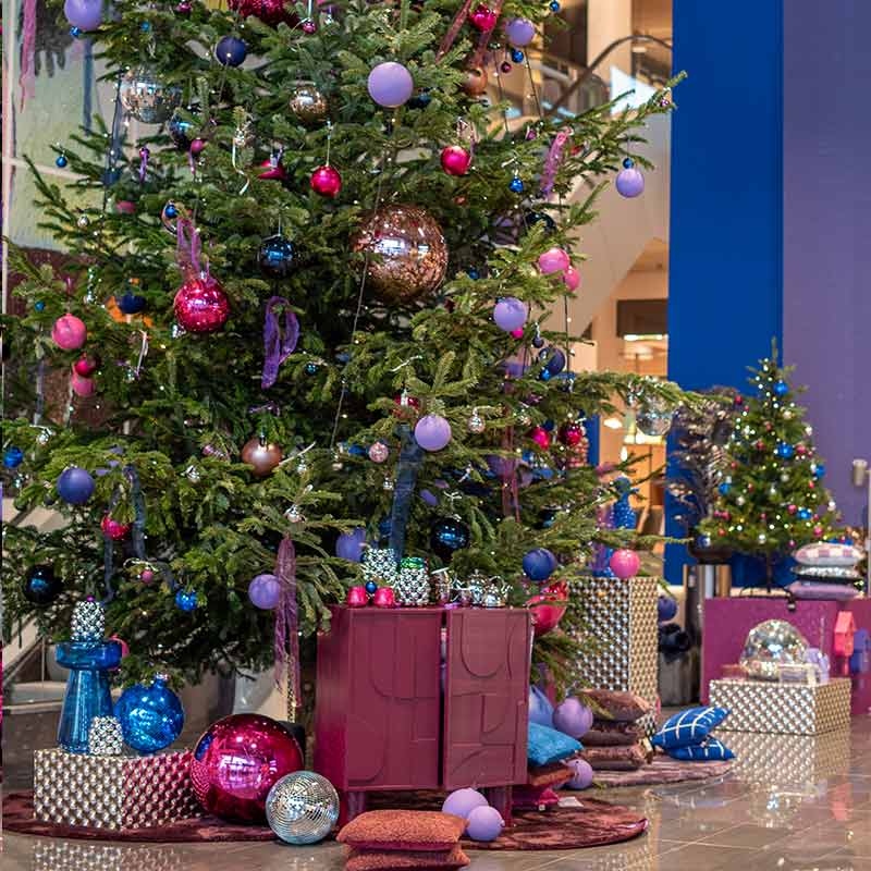 Gekleurde kerstboom in centrale hal bij home center 