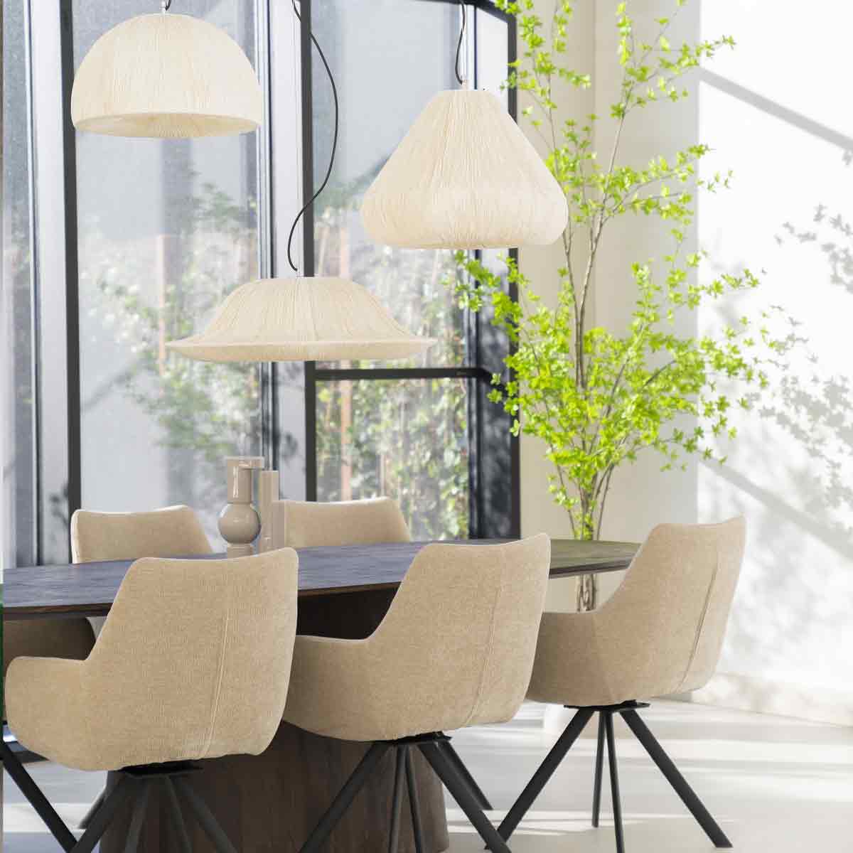 Een zithoek met crèmekleurige brede eetkamerstoelen, een zwarte eettafel van witte lampen van organische vormen.