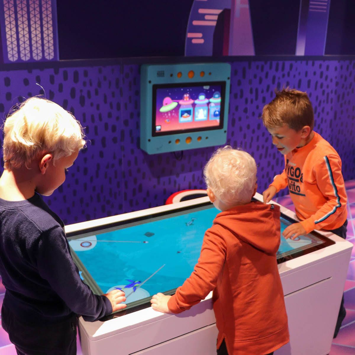 Een blij kind in een blauwe glijbaan in het kinderdorp van Home Center