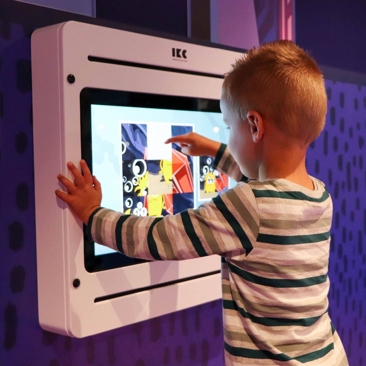 Een blij kind in een blauwe glijbaan in het kinderdorp van Home Center