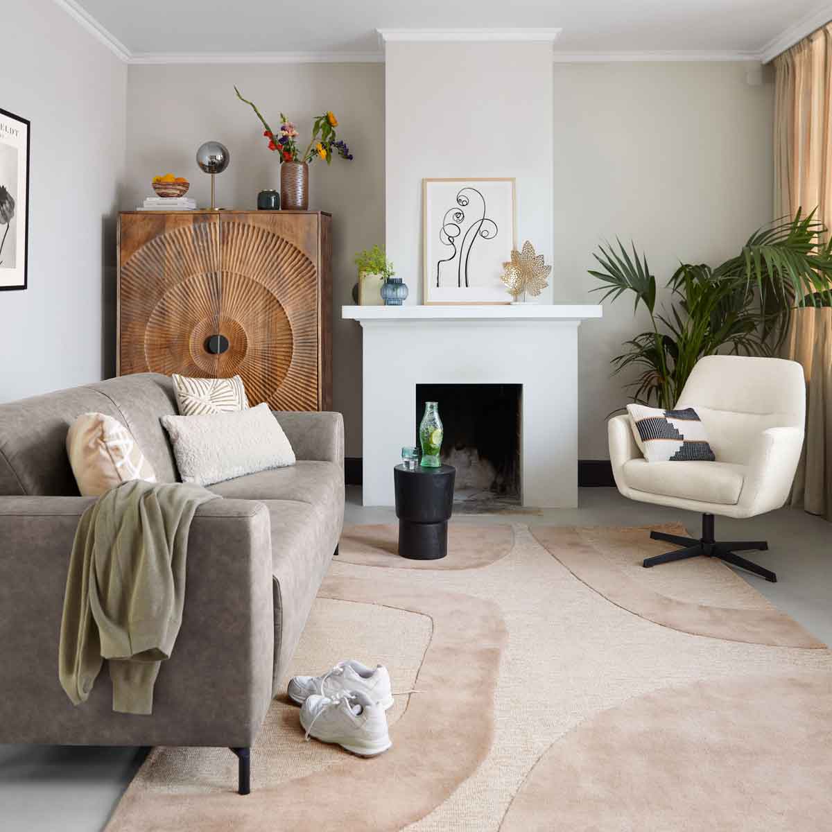 Een kleine woonkamer met groene zitbank van Profijt en witte fauteuil