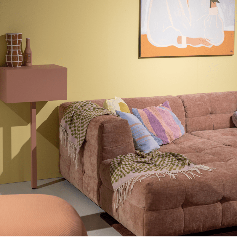Zachte witte fauteuil met kussens, roze wand en stijlvolle decoratieve accessoires