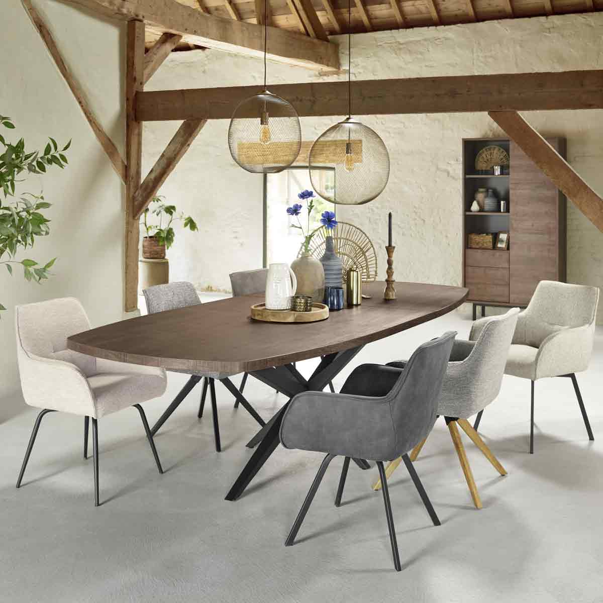 Een rustieke eethoek met 6 eetkamerstoelen in witte, grijze en zwarte tinten aan een lange bruine tafel