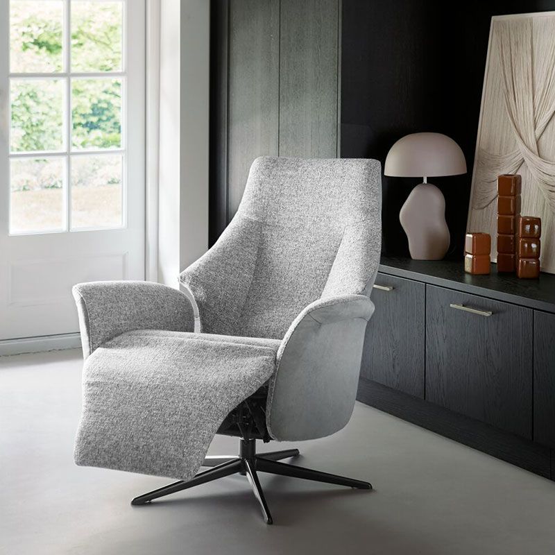 Luxe relaxfauteuil met voetenbank, groene bekleding en houten details bij licht raam