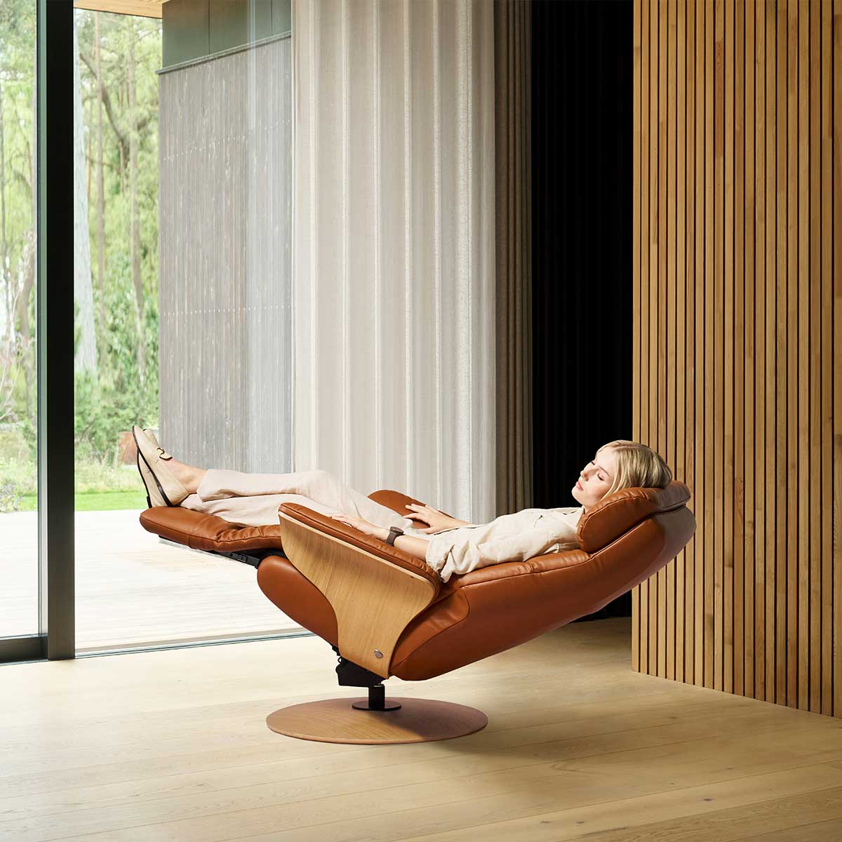 Relaxfauteuil met hartbalans functie, lichte bekleding en houten details in warme, rustige setting