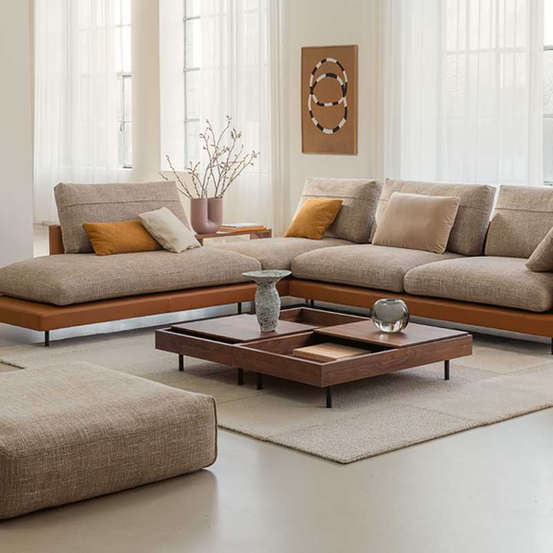 Luxe design hoekbank van Rolf Benz met beige stoffering en leren basis in moderne, lichte woonkamer.