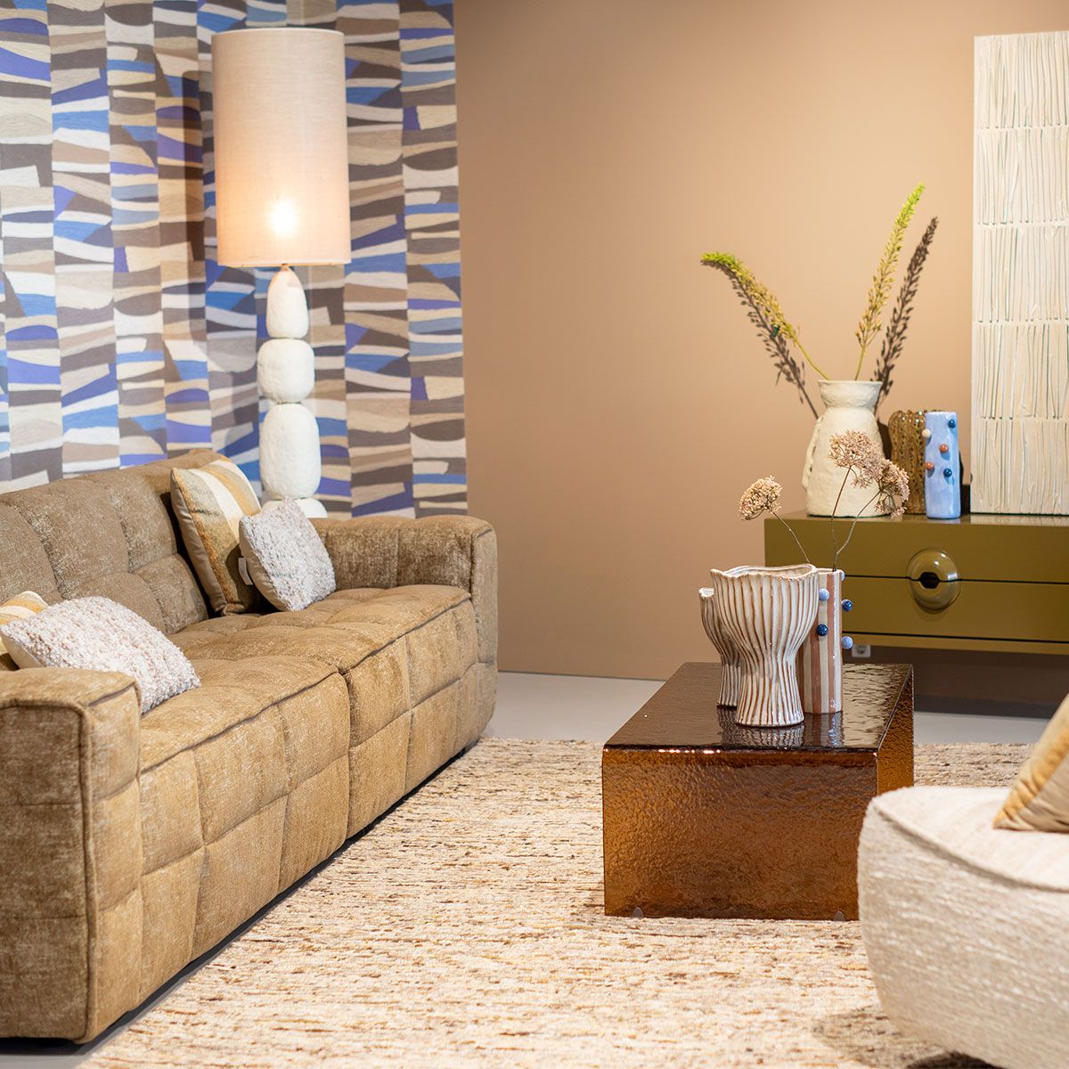 Moderne beige stoffen bank met afgeronde vormen in lichte woonkamer met groot raam