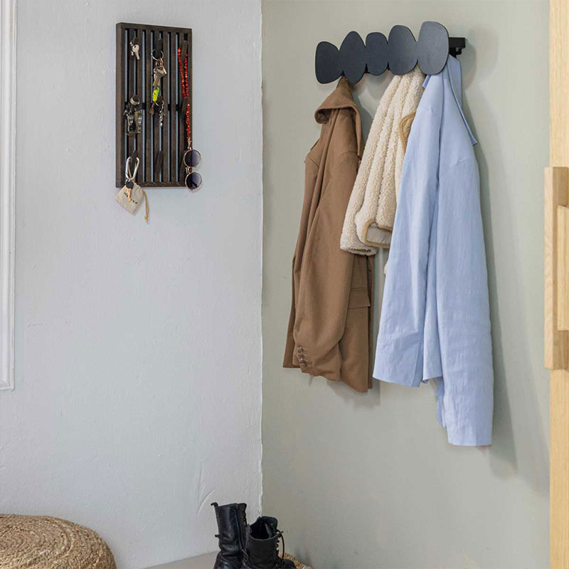 Praktische halinrichting met kapstok, sleutelrek en jassen in compacte entree met rustige kleuren