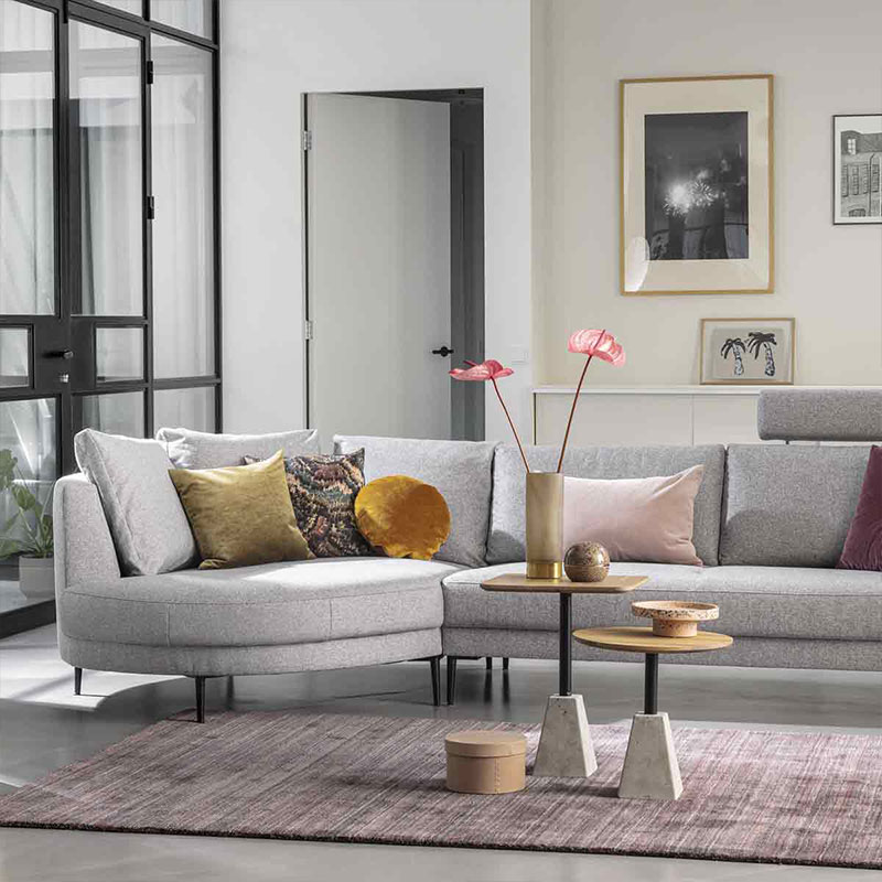 Lichtgrijze hoekbank met kleurrijke kussens en accessoires in moderne woonkamer met glazen deur