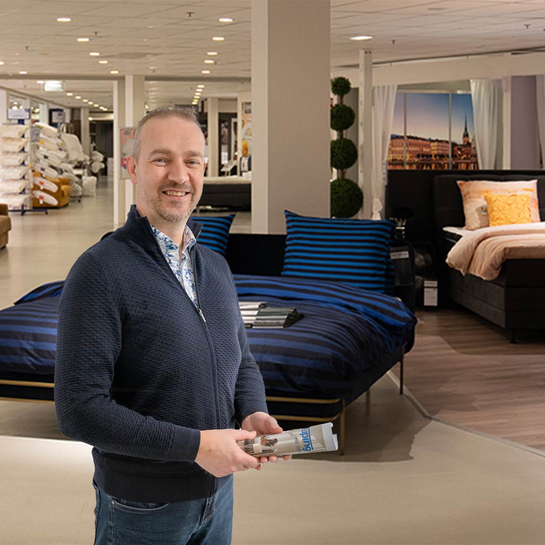 Een mannelijke beddenverkoper met een magazine in een beddenshowroom met opgemaakte bedden