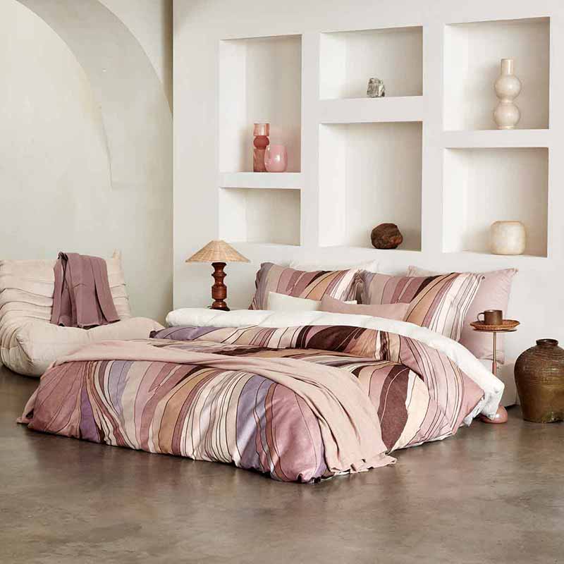 Een roze bed in een lichte slaapkamer met roze dekens van Auping