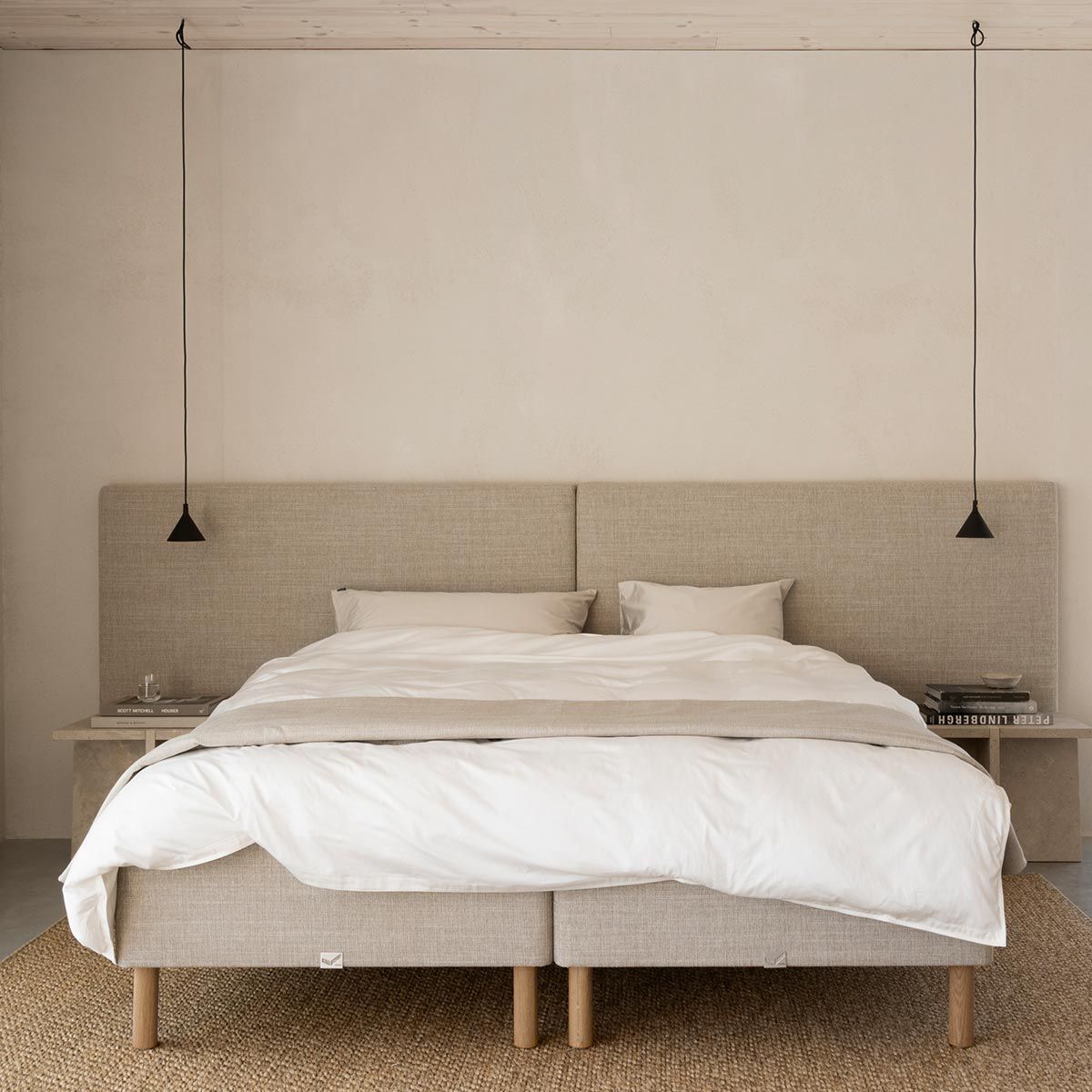 Minimalistische slaapkamer met beige boxspring, linnen hoofdbord, hanglampen en rustige neutrale tinten