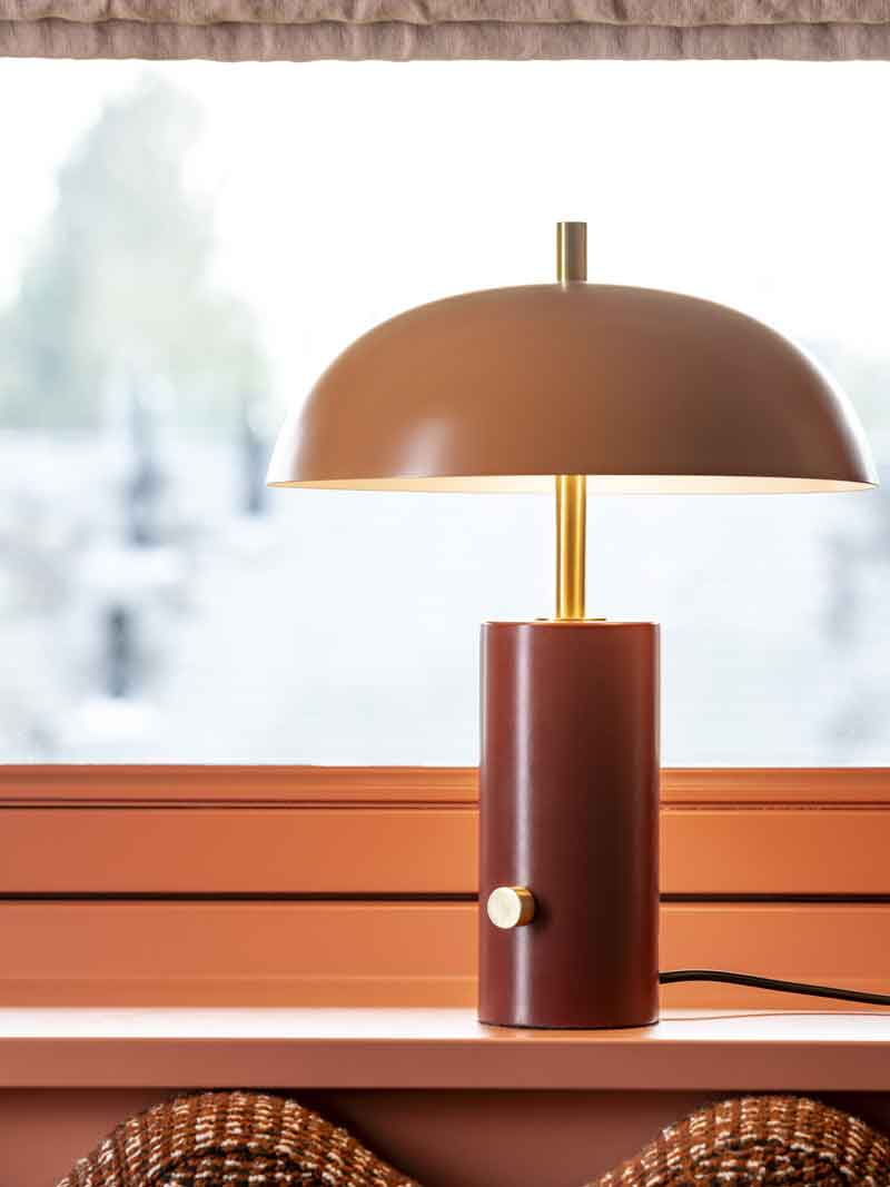 Een kleine tafellamp met rood en oranje kleuren in een vensterbank