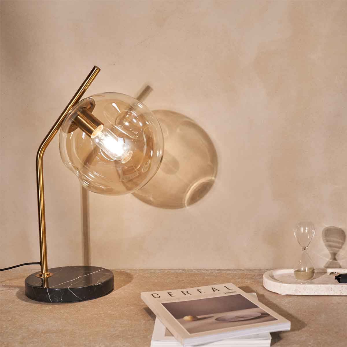 Een kleine tafellamp met grote lichtbron op een bureau