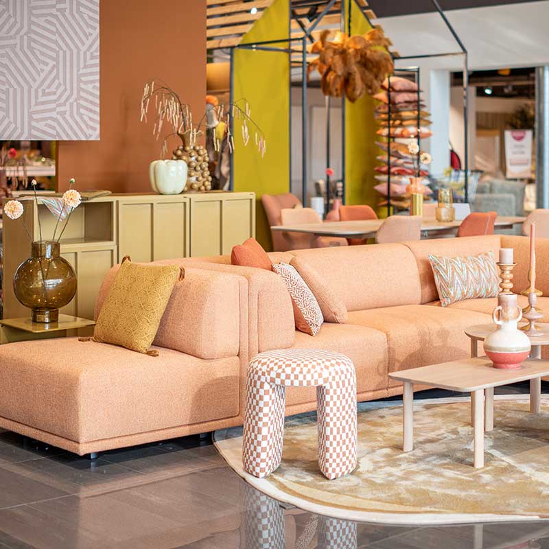 Warme woonkamer met oranje bank, speelse accessoires, ronde vormen en zachte pastelkleuren