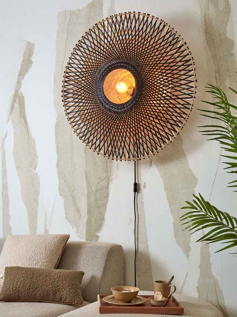 Een ronde wandlamp in boho-stijl van riet met een lichtbron in het midden