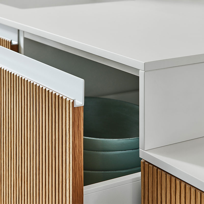 Close-up van keukenlade met wit blad en houten front met verticale groeven