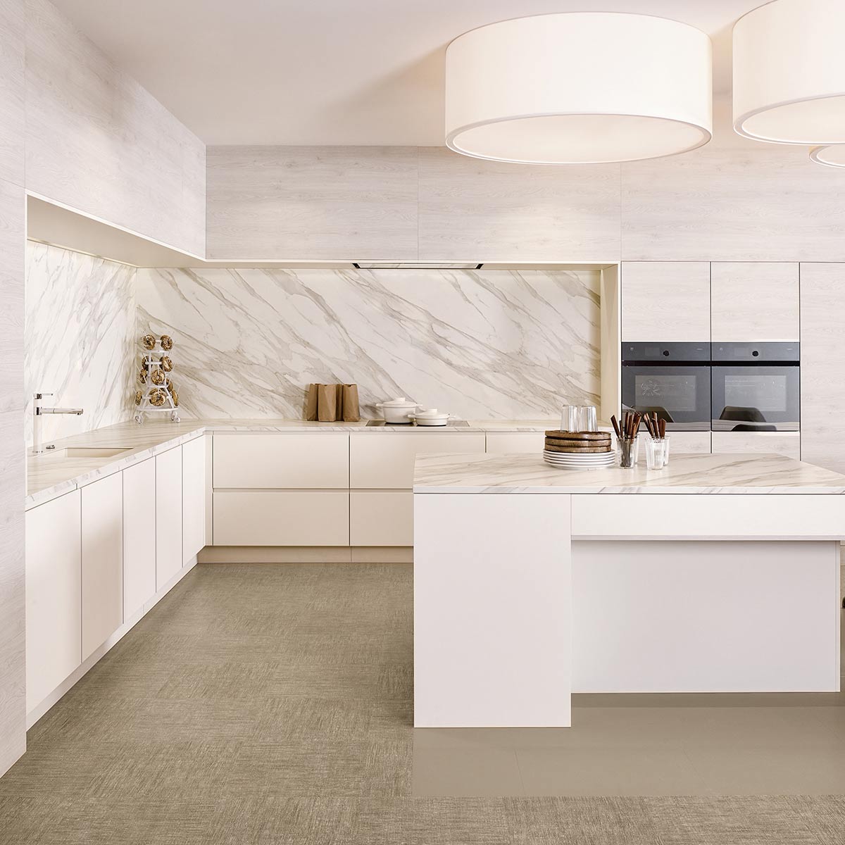 Strakke witte keuken met marmeren werkblad, kookeiland en ingebouwde ovens in moderne stijl