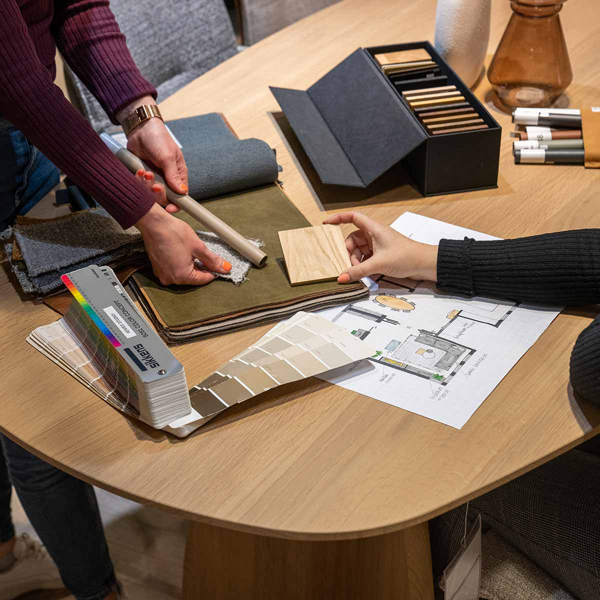 Interieuradvies met stalen, kleurenwaaiers en plattegrond tijdens inspirerend woonadvies aan houten tafel