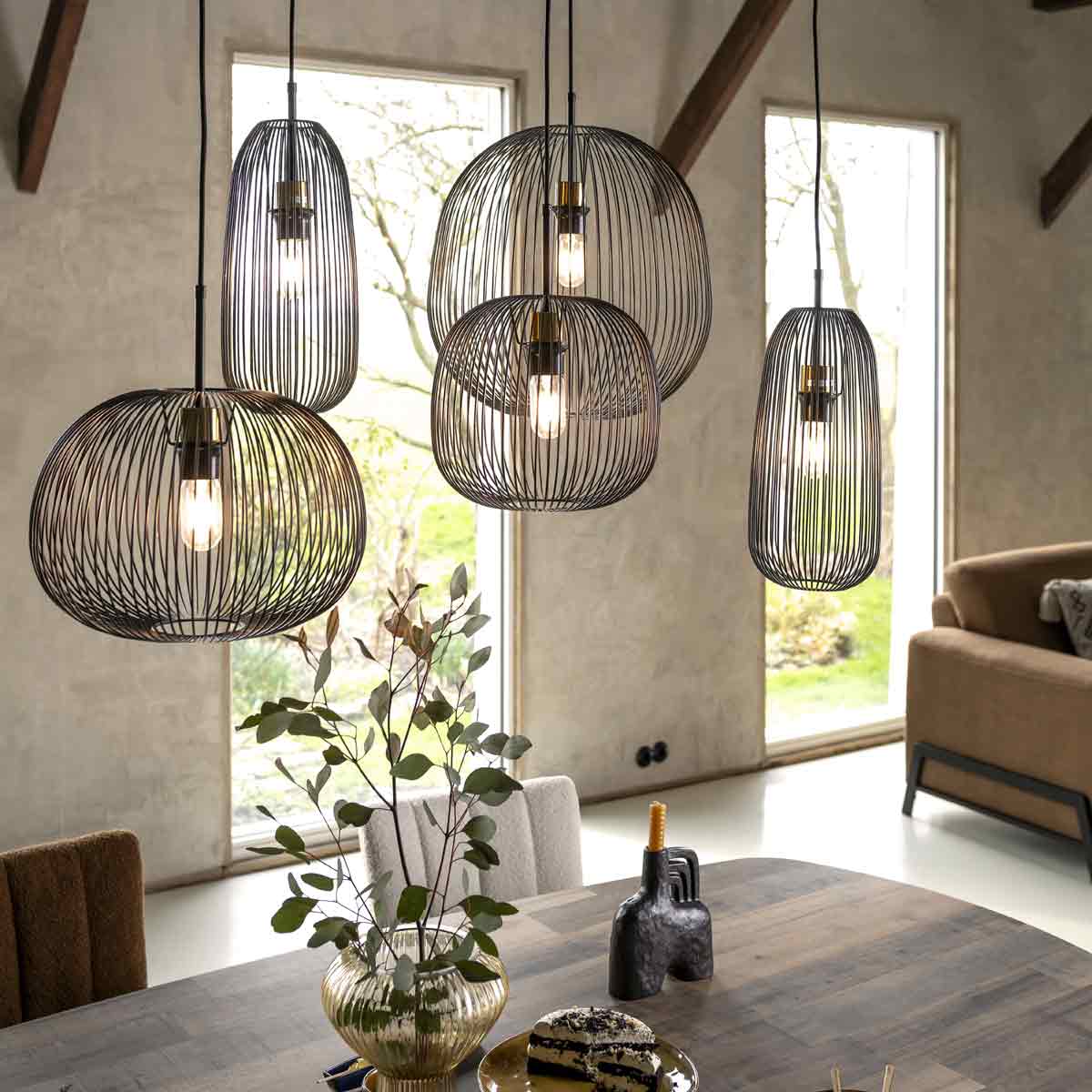 5 zwarte hanglampen in organische vormen boven een eettafel