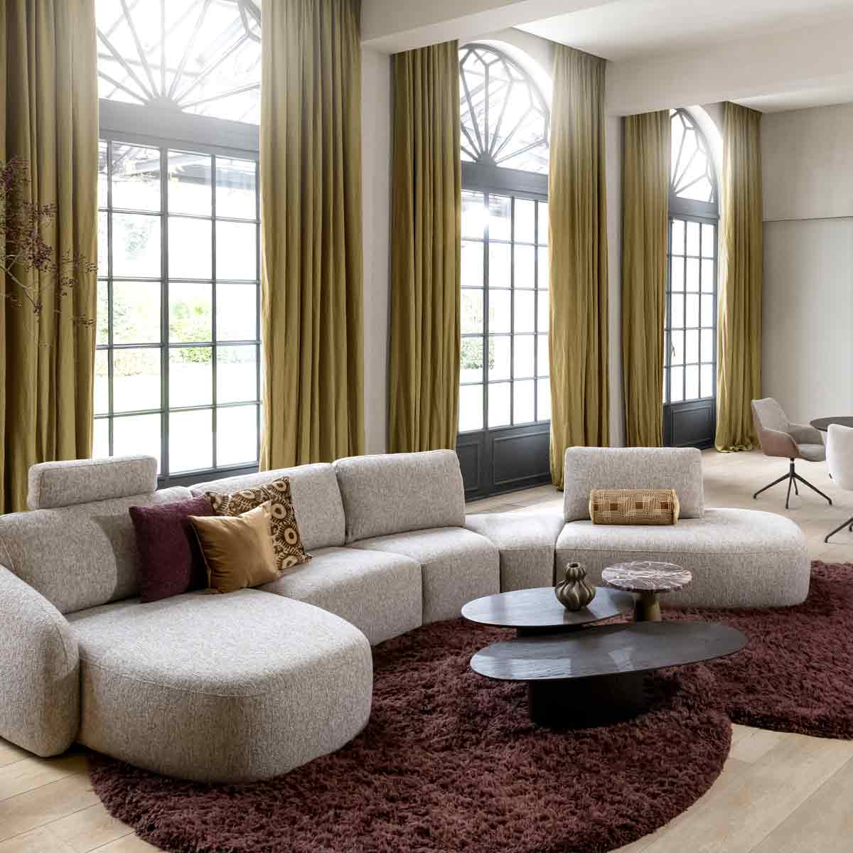 Grijze hoekbank van Xooon met rode kussens en zwarte bijzettafels