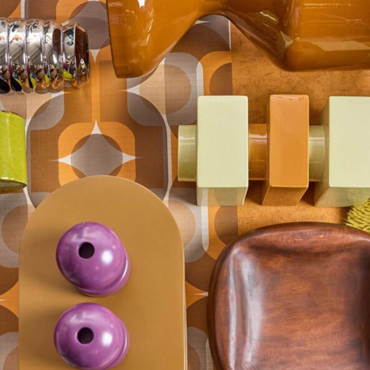 Retro woonaccessoires in oranje, groen en paars op grafisch patroon in bruine tinten