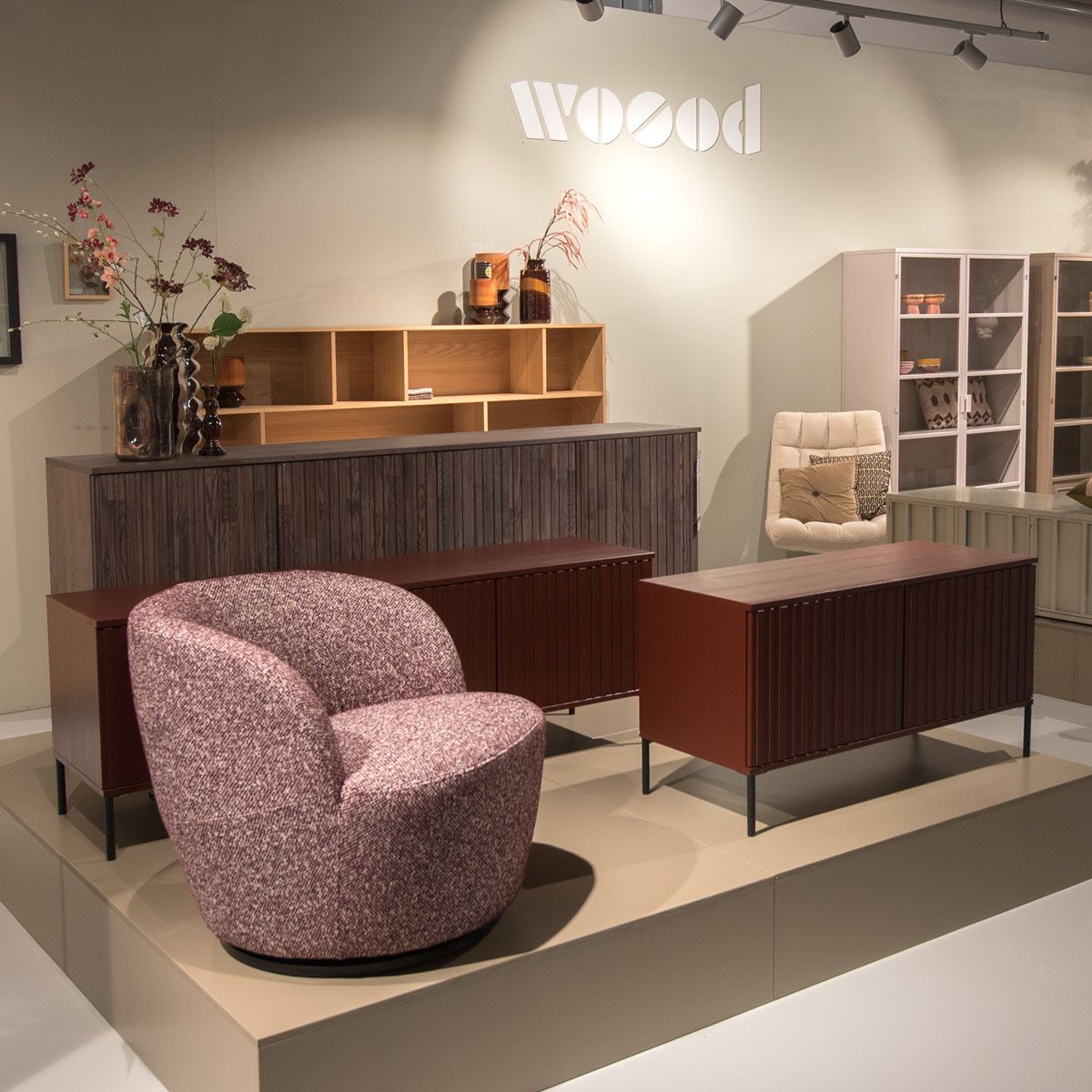 WOOOD showroom met roze fauteuil, lage kasten, vitrinekasten en houten wandkast