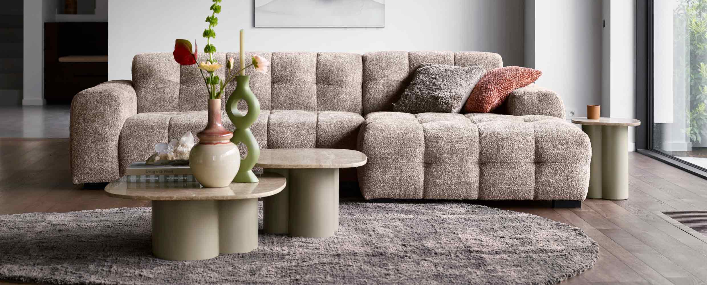 Blokbank van INHOUSE met zachtroze kleur en twee bijzettafels in neutrale kleuren.